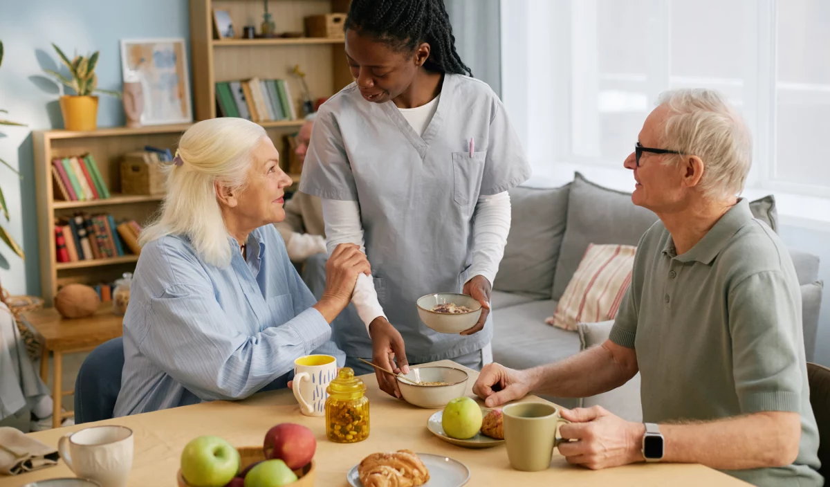 Une préposée discute avec deux résidents dans la salle à manger du Jardin des sages après un repas.