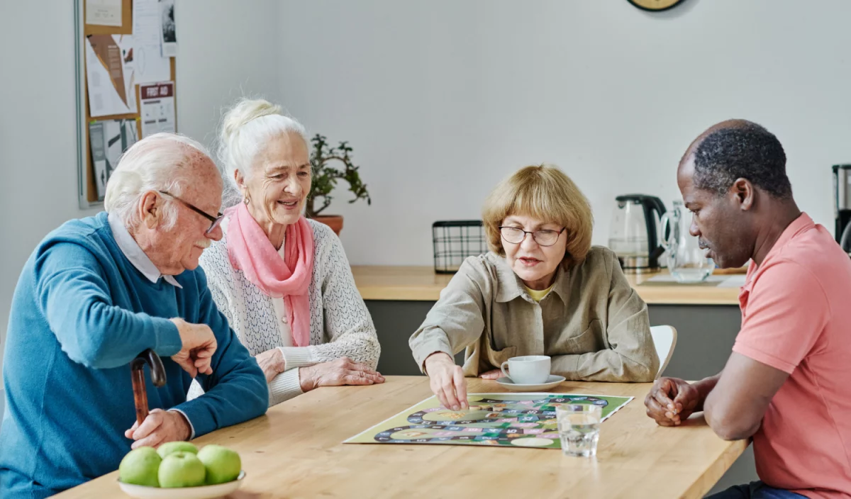 Des résidents jouent à un jeu de société et échangent dans une ambiance conviviale au Jardin des sages.